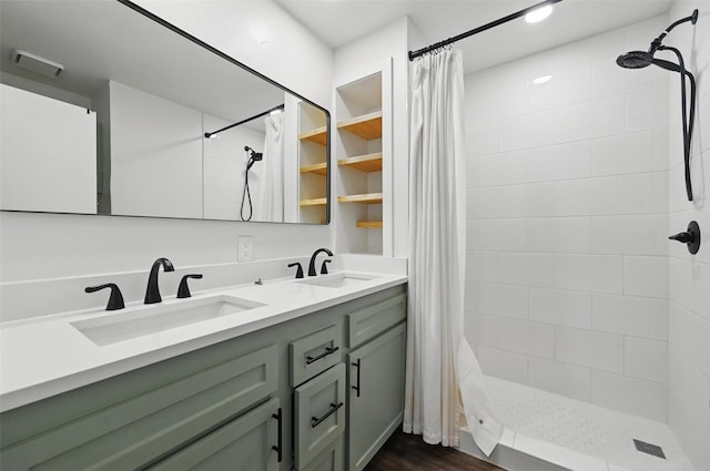full bathroom with double vanity, a tile shower, and a sink