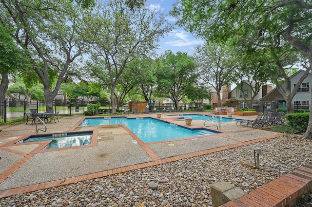 community pool with fence, a community hot tub, and a patio area