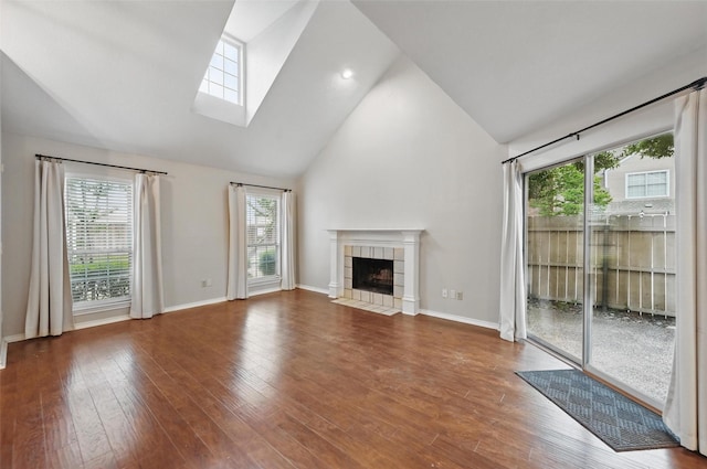 unfurnished living room with plenty of natural light, a tiled fireplace, and a skylight