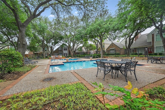 pool with a patio area, fence, and a jacuzzi