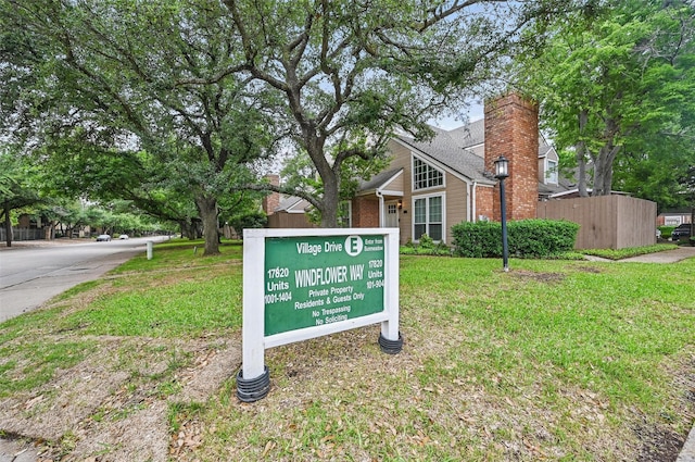 community / neighborhood sign with a yard and fence