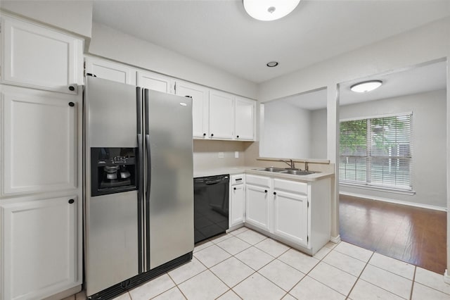 kitchen with a sink, dishwasher, white cabinetry, stainless steel fridge, and light countertops