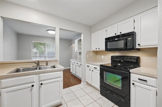 kitchen featuring light tile patterned floors, a sink, black appliances, light countertops, and white cabinets