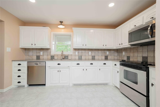 kitchen with light stone countertops, a sink, backsplash, stainless steel appliances, and white cabinets
