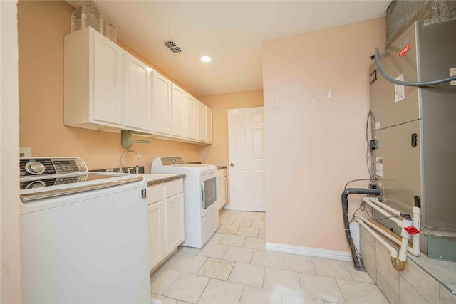 laundry area featuring washer and dryer, a sink, cabinet space, visible vents, and light tile patterned flooring