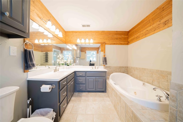 full bathroom featuring double vanity, a tub with jets, toilet, and a sink