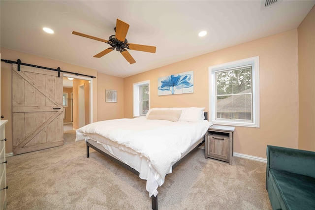 bedroom with light colored carpet, a barn door, baseboards, and multiple windows