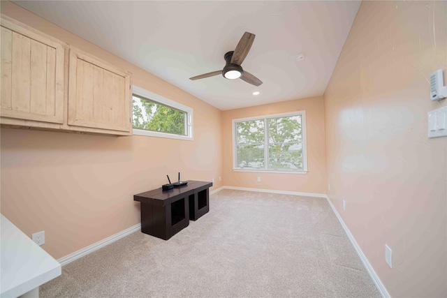unfurnished office with ceiling fan, light colored carpet, baseboards, and a healthy amount of sunlight