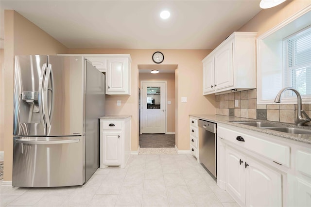 kitchen with backsplash, white cabinetry, stainless steel appliances, and a sink