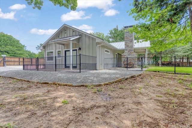 10 Holland St, Pottsboro, TX 75076 - back of property featuring a chimney, board and batten siding, a standing seam roof, a patio, and metal roof