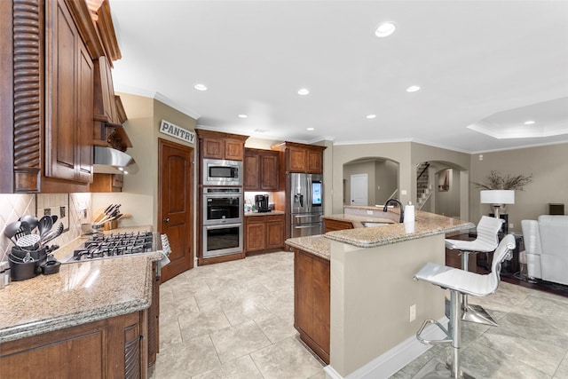 10528 Lago Vis, Quinlan, TX 75474 - kitchen with a sink, backsplash, a kitchen bar, arched walkways, and appliances with stainless steel finishes