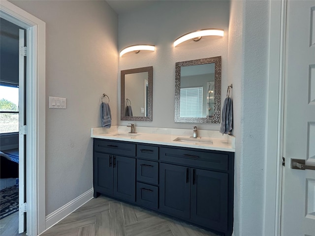 full bathroom with baseboards, double vanity, and a sink