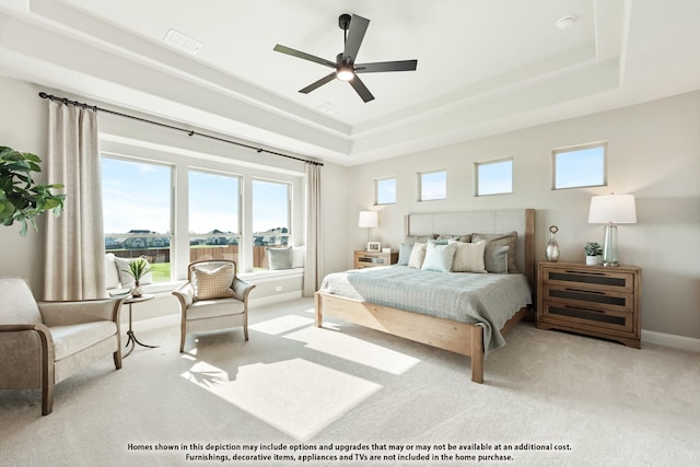 carpeted bedroom with a tray ceiling, ceiling fan, baseboards, and visible vents