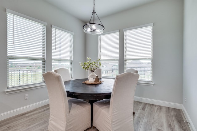 dining area with baseboards, an inviting chandelier, and light wood-type flooring
