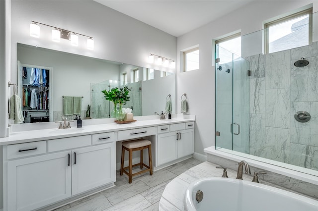 bathroom with a stall shower, double vanity, a sink, and a washtub