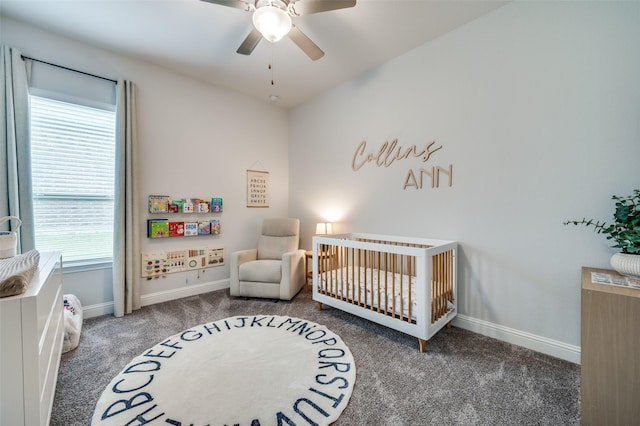 carpeted bedroom with a crib, baseboards, and ceiling fan