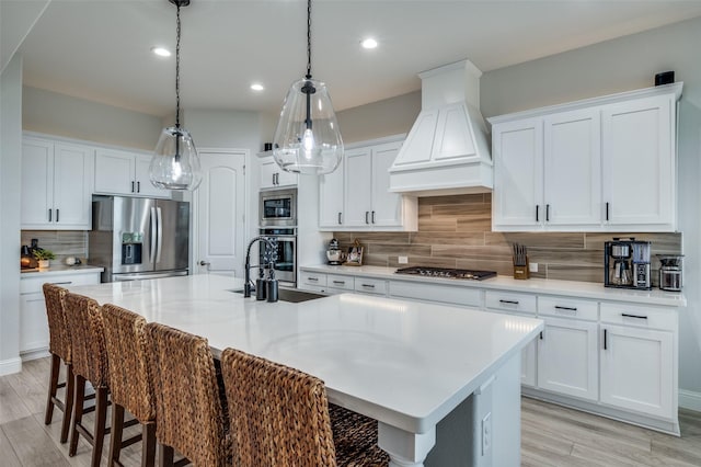 kitchen with decorative backsplash, light wood-style flooring, a breakfast bar, appliances with stainless steel finishes, and premium range hood