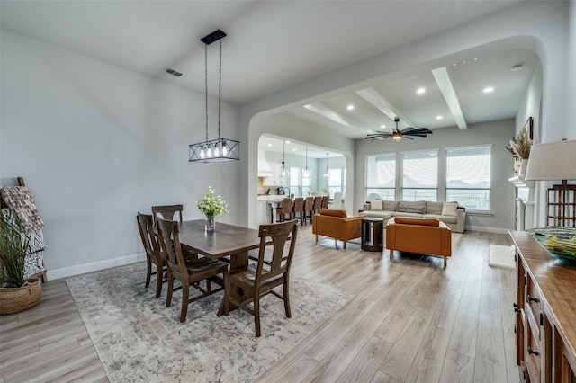 dining room with light wood-style flooring, a ceiling fan, beam ceiling, visible vents, and arched walkways
