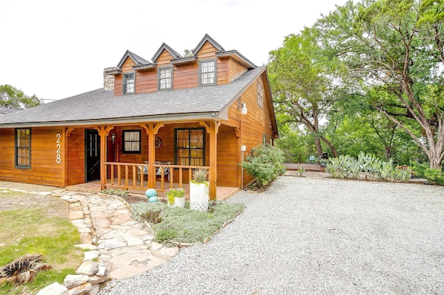 chalet / cabin featuring covered porch, a shingled roof, and driveway