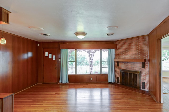 2000 Standifer St, Fort Worth, TX 76164 - unfurnished living room with light wood-type flooring, wood walls, and a fireplace