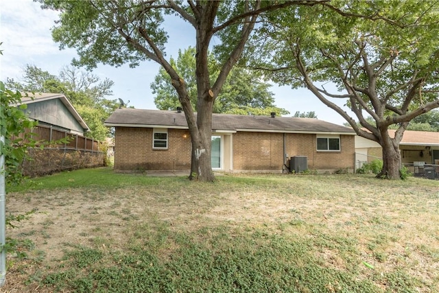 back of house featuring brick siding, central AC unit, and fence