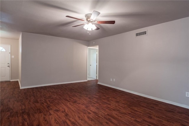 unfurnished room featuring baseboards, ceiling fan, dark wood finished floors, and visible vents