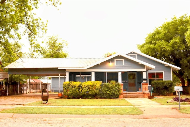 craftsman house featuring covered porch, fence, a front yard, and a carport