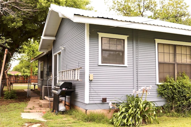 view of side of property with metal roof, fence, and central air condition unit