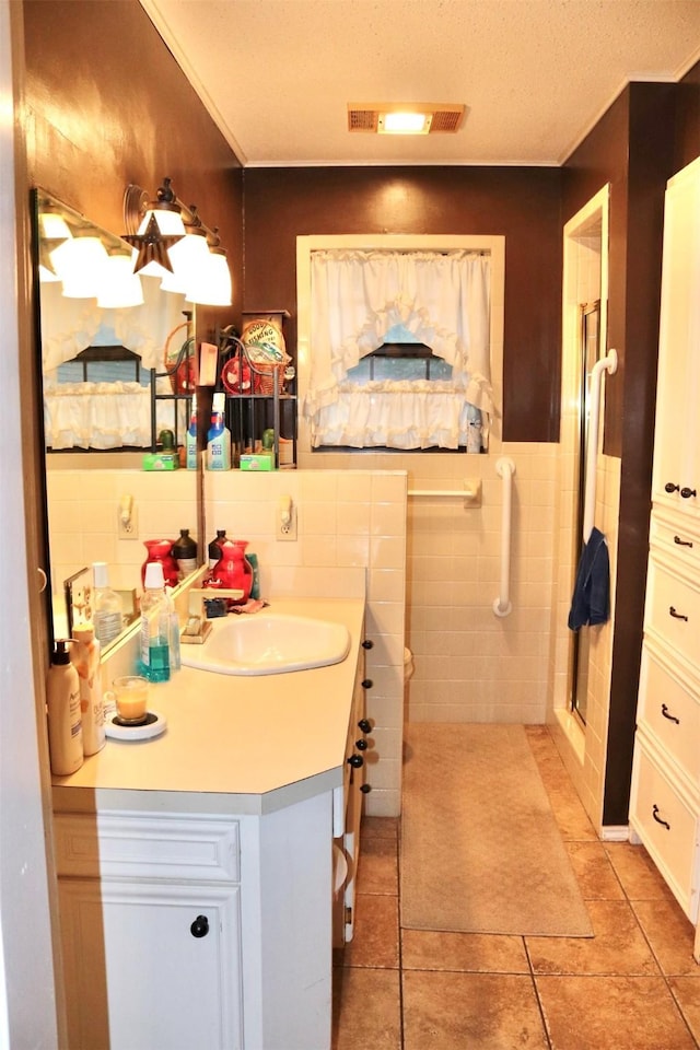 bathroom with tile walls, visible vents, a shower stall, tile patterned flooring, and vanity