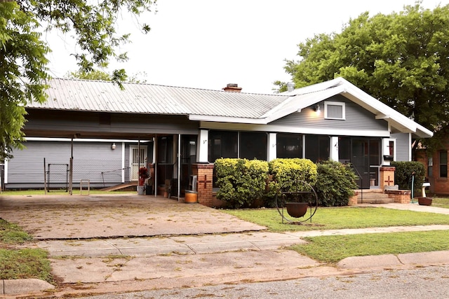 view of front of house with a chimney, metal roof, a front lawn, and driveway