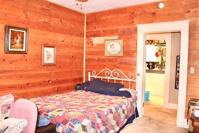 bedroom featuring ensuite bathroom, wood walls, and carpet floors
