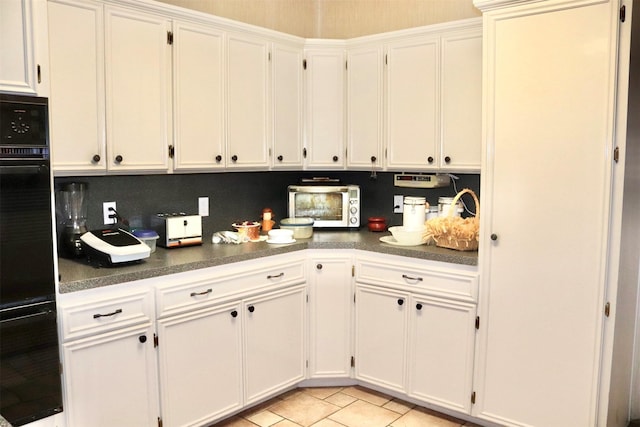 kitchen with oven, white cabinetry, dark countertops, and a toaster