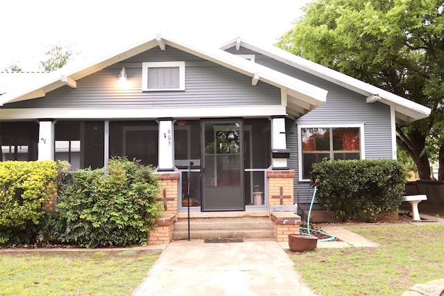 bungalow-style home with entry steps, brick siding, and a front yard
