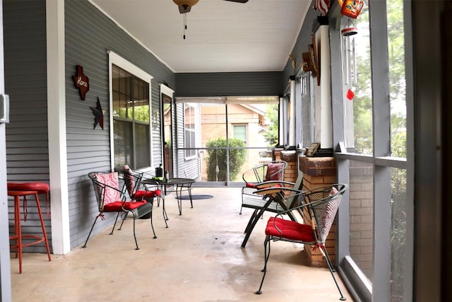 sunroom / solarium featuring ceiling fan and concrete flooring