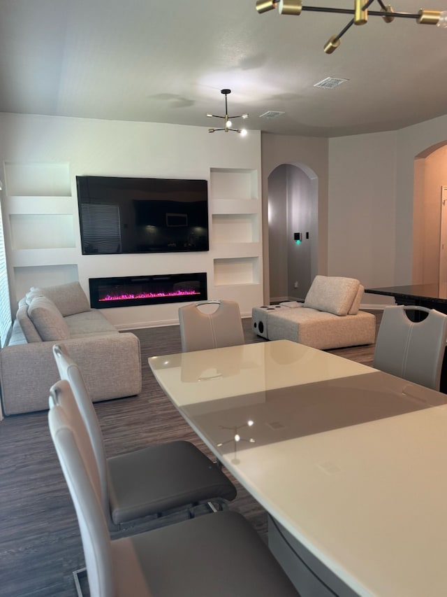 living room with built in features, visible vents, arched walkways, and a glass covered fireplace