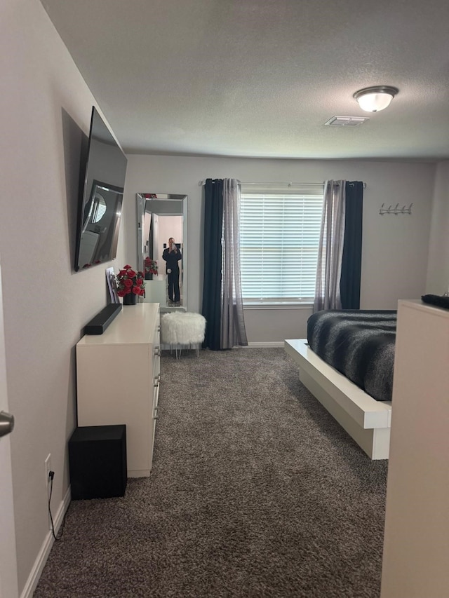 carpeted bedroom with baseboards, visible vents, and a textured ceiling