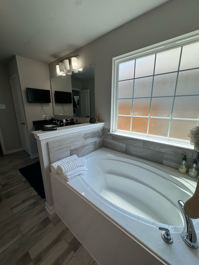 full bathroom with a garden tub, baseboards, and wood finished floors