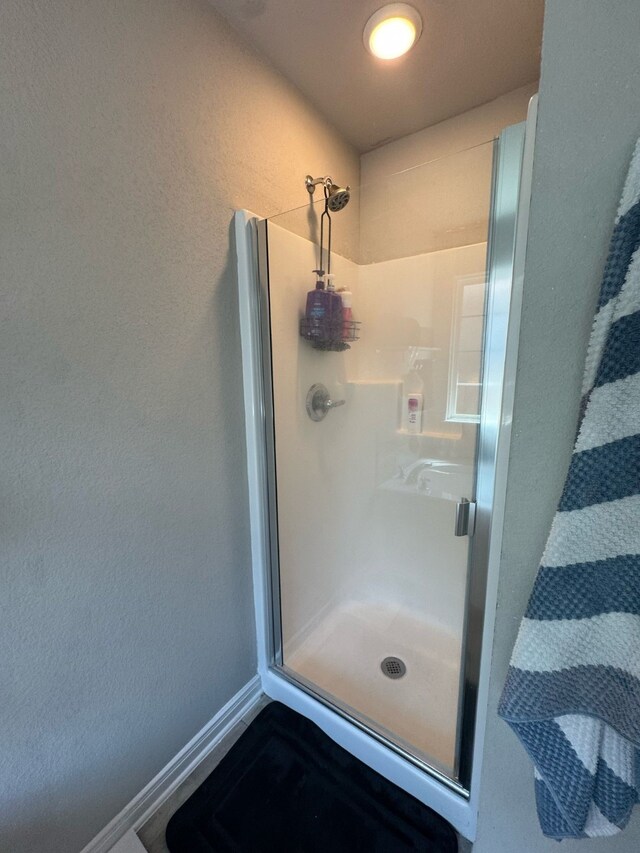 full bath featuring a stall shower and baseboards