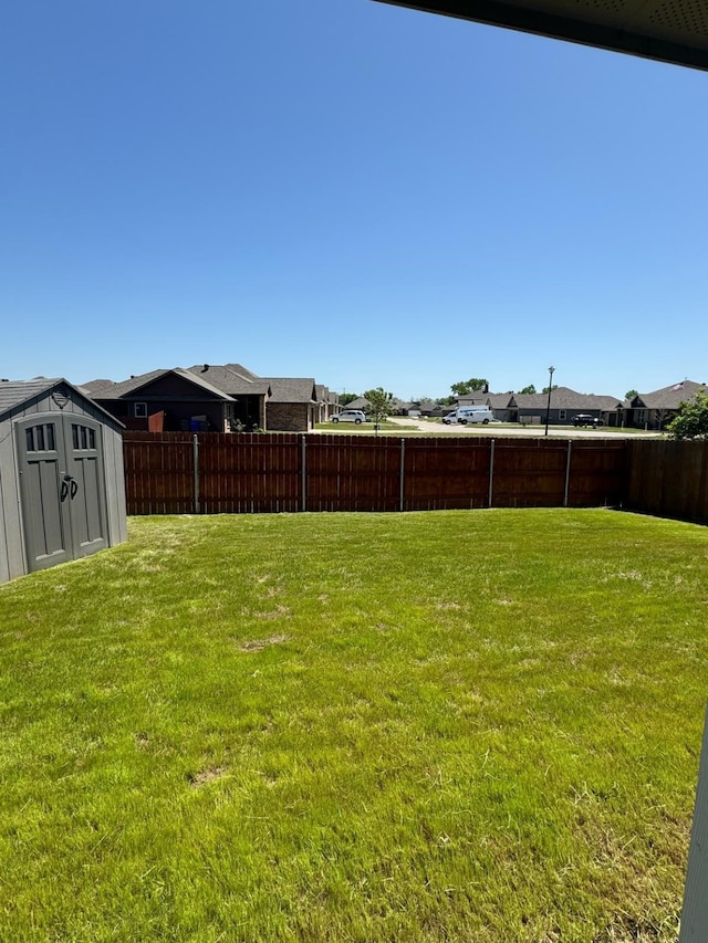 view of yard with a fenced backyard, a storage shed, an outdoor structure, and a residential view