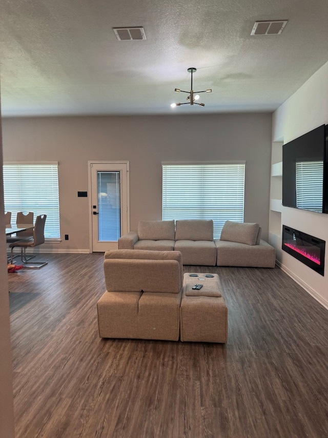living room with a glass covered fireplace, baseboards, visible vents, and wood finished floors