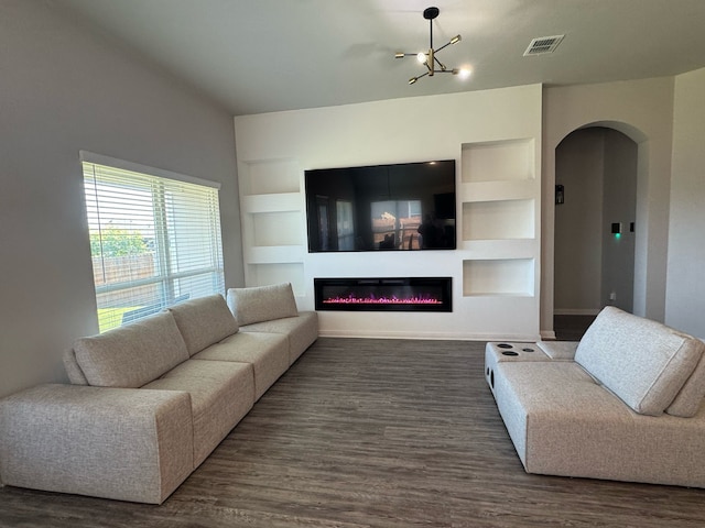 living room with dark wood finished floors, visible vents, arched walkways, and built in features