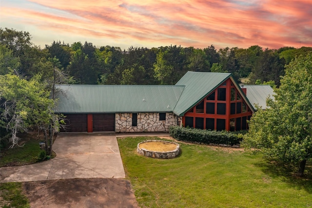 cabin with a lawn, driveway, an attached garage, and metal roof