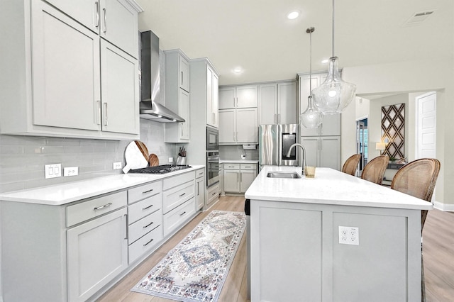 1504 Bearpath Way, Gunter, TX 75058 - kitchen featuring wall chimney exhaust hood, stainless steel appliances, light wood-type flooring, a kitchen island with sink, and decorative backsplash