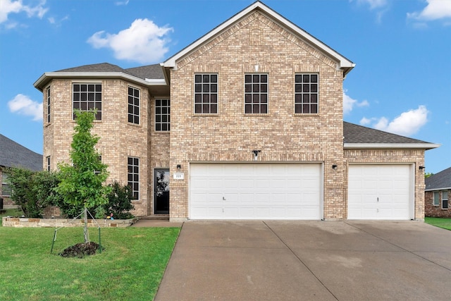 traditional home with a front lawn, a shingled roof, brick siding, and driveway