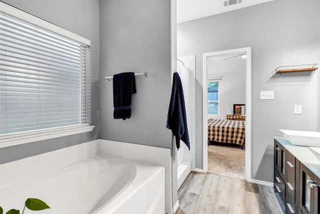 bathroom with a bath, connected bathroom, wood finished floors, and a stall shower