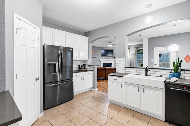 kitchen with a ceiling fan, a sink, dark countertops, fridge with ice dispenser, and dishwasher