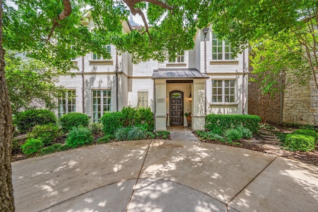 townhome / multi-family property with a standing seam roof and brick siding