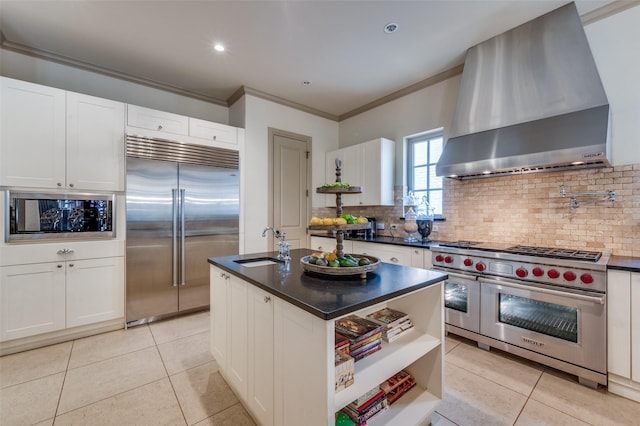 kitchen featuring built in appliances, dark countertops, light tile patterned flooring, and wall chimney exhaust hood