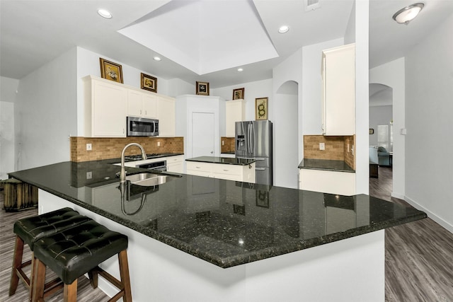 10110 Andre Dr, Irving, TX 75063 - kitchen with dark wood-style flooring, a sink, decorative backsplash, arched walkways, and stainless steel appliances