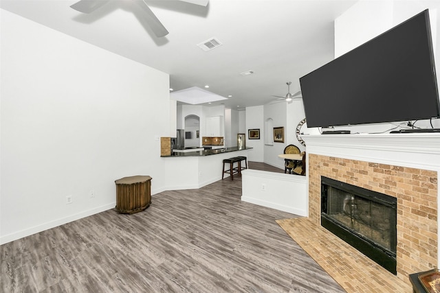 10110 Andre Dr, Irving, TX 75063 - living room with wood finished floors, visible vents, ceiling fan, baseboards, and a fireplace with flush hearth